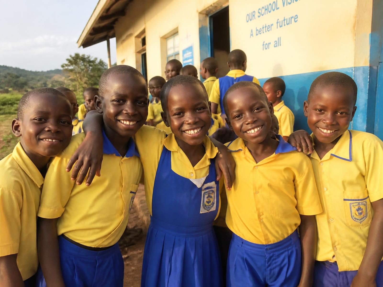 Schoolchildren smiling together outside their classroom in Uganda